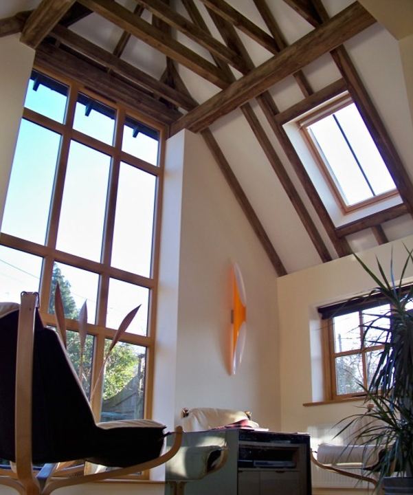 Interior of a barn-style extension with a vaulted ceiling, exposed timber beams and a tall window