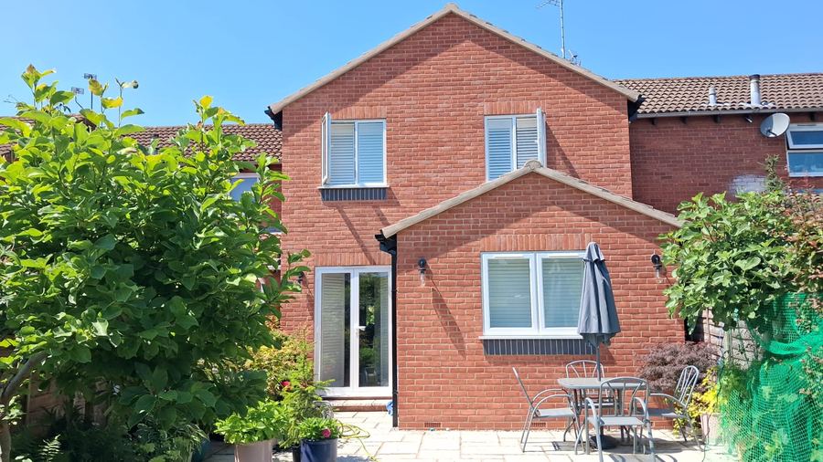 Twin gable single storey rear extension in red brick with French doors and a raised patio