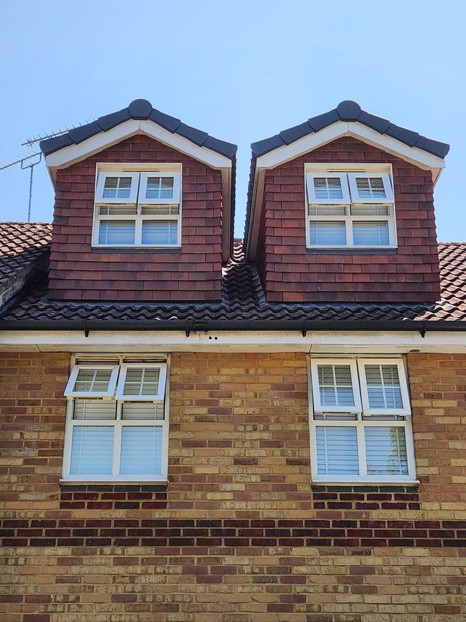A pair of tile hung dormer windows in a pitched roof