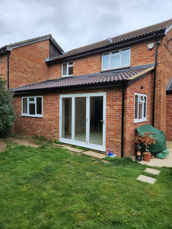 Brick rear extension with white bifold doors and a tiled lean-to roof