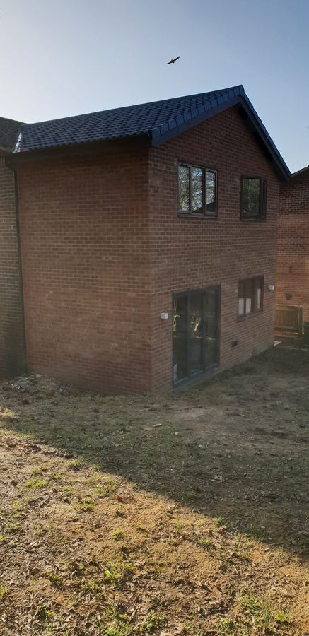 Two storey brick side extension with a dark tiled roof